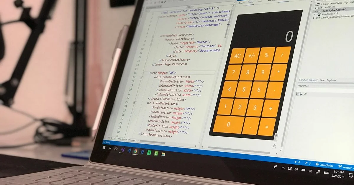 Un écran d'ordinateur portable affiche une application de codage avec un design de calculatrice dans un bureau technologique.